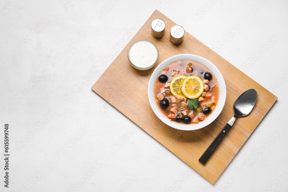 Bowl of tasty Hodgepodge soup with sour cream on light background