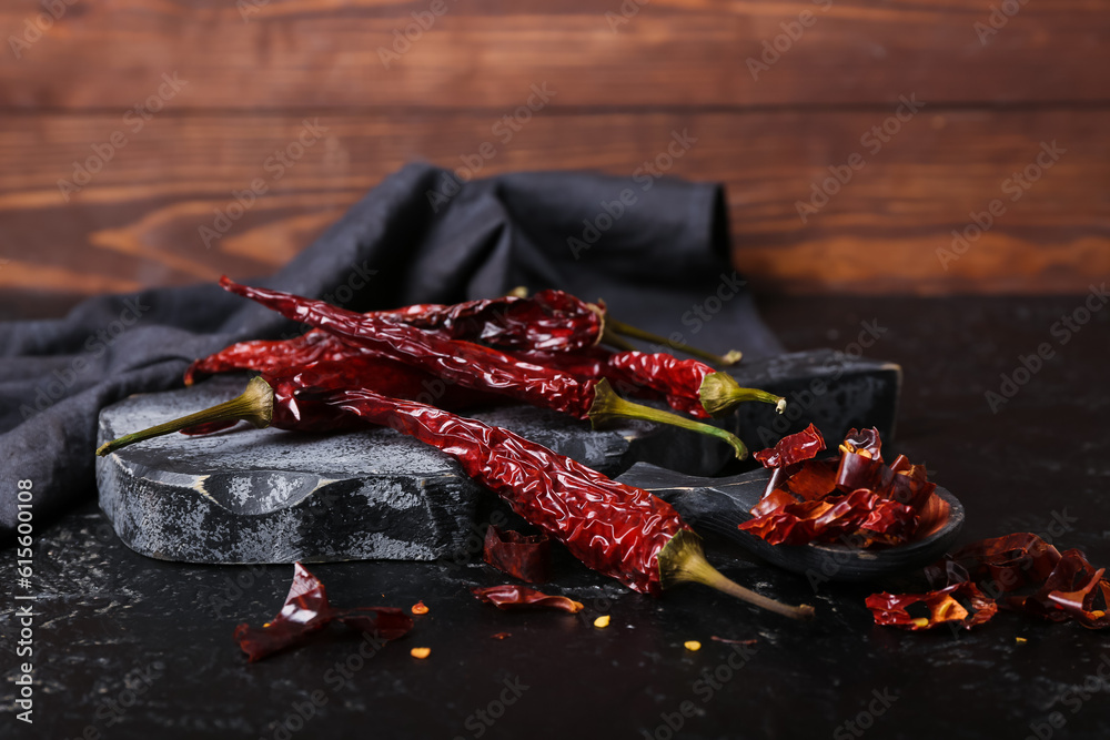 Board with dry hot chili peppers on dark background