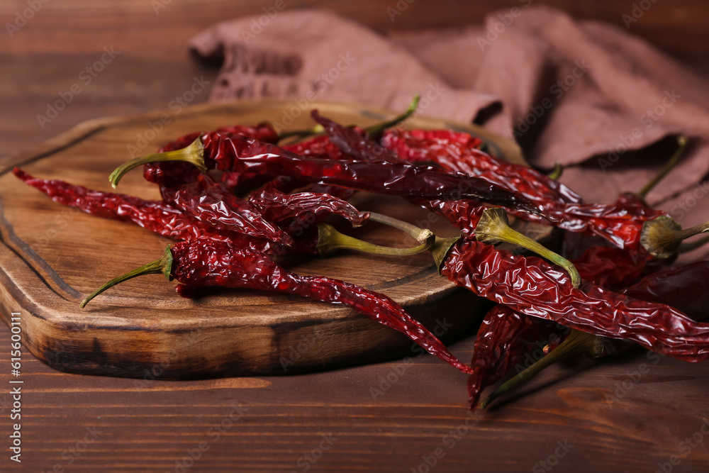 Board with dry hot chili peppers on brown wooden background