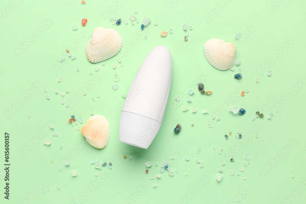 Deodorant with shells and sea salt on light green background