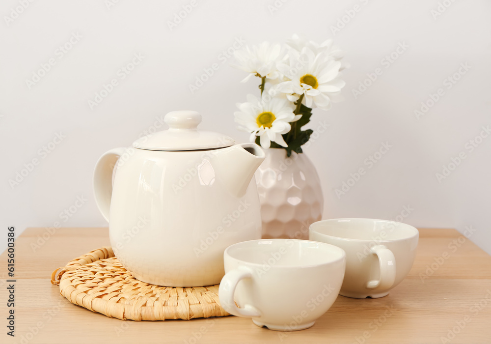 Tea set with wicker mat and flowers  on wooden table