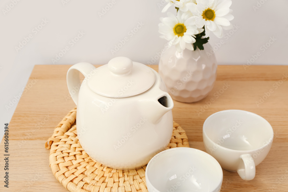 Tea set with wicker mat and flowers  on wooden table