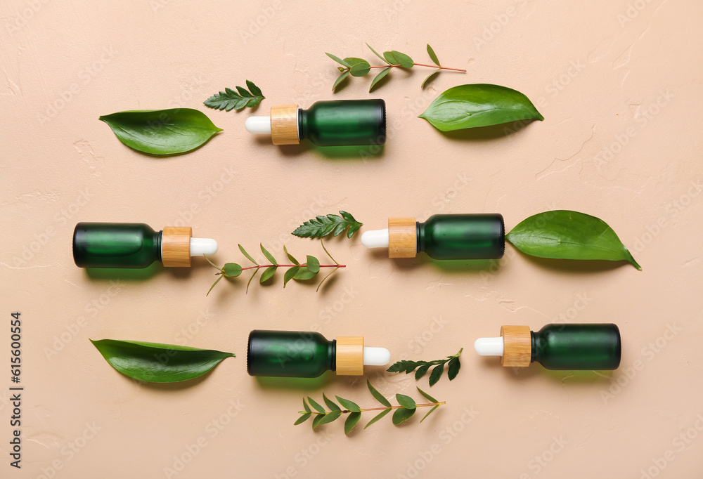 Bottles of cosmetic oil with plant twigs on beige background