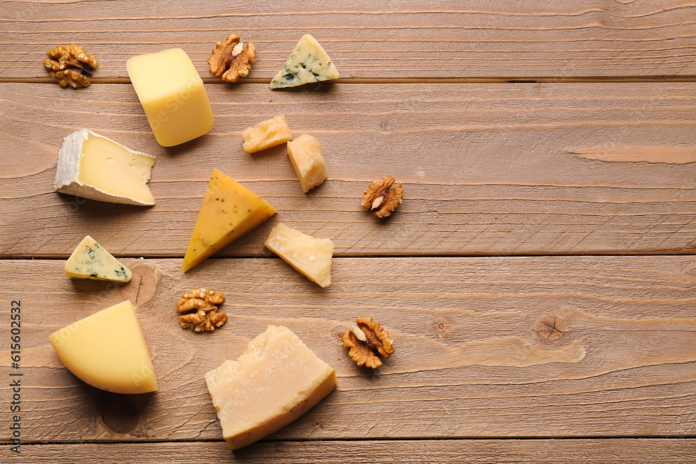 Pieces of tasty cheese with nuts on wooden background