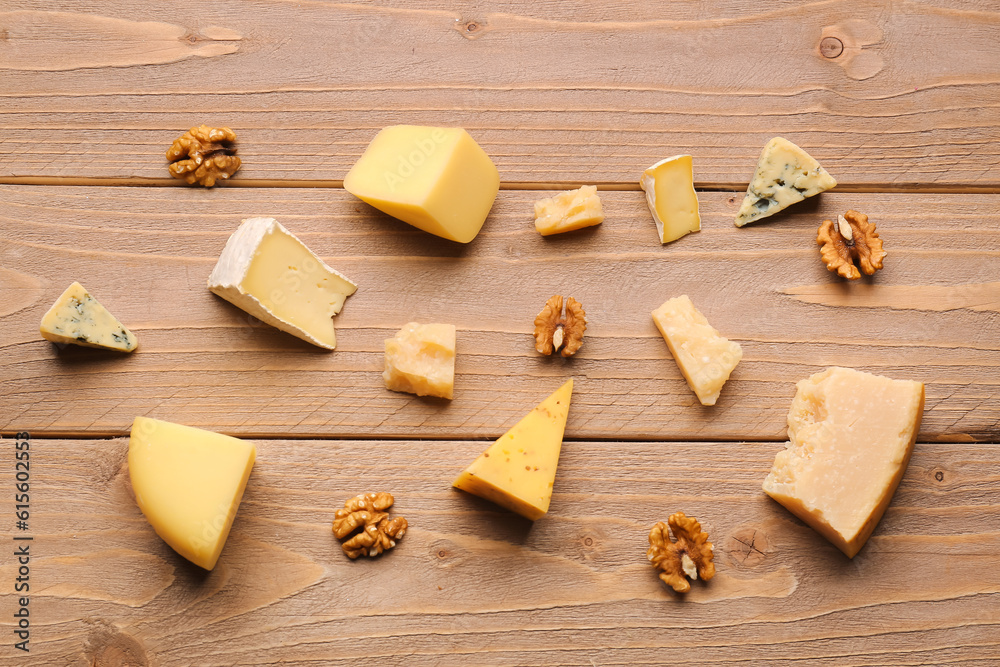 Pieces of tasty cheese with nuts on wooden background