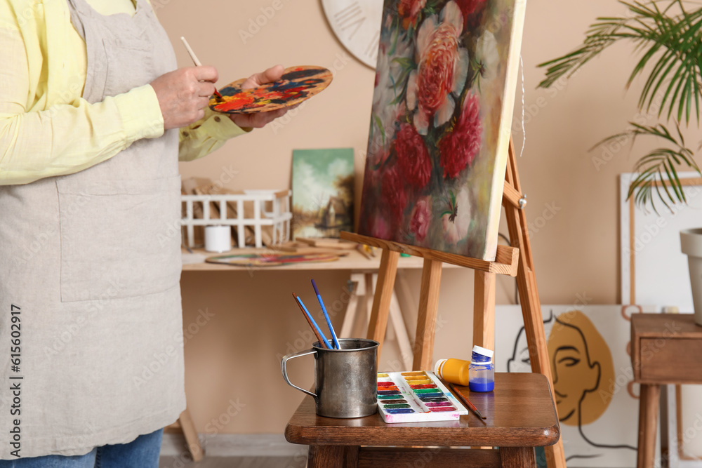 Mature female artist painting picture in  workshop