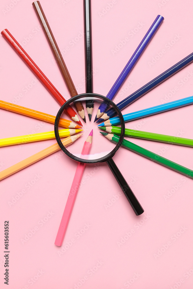 Magnifier with frame made of colorful pencils on pink background