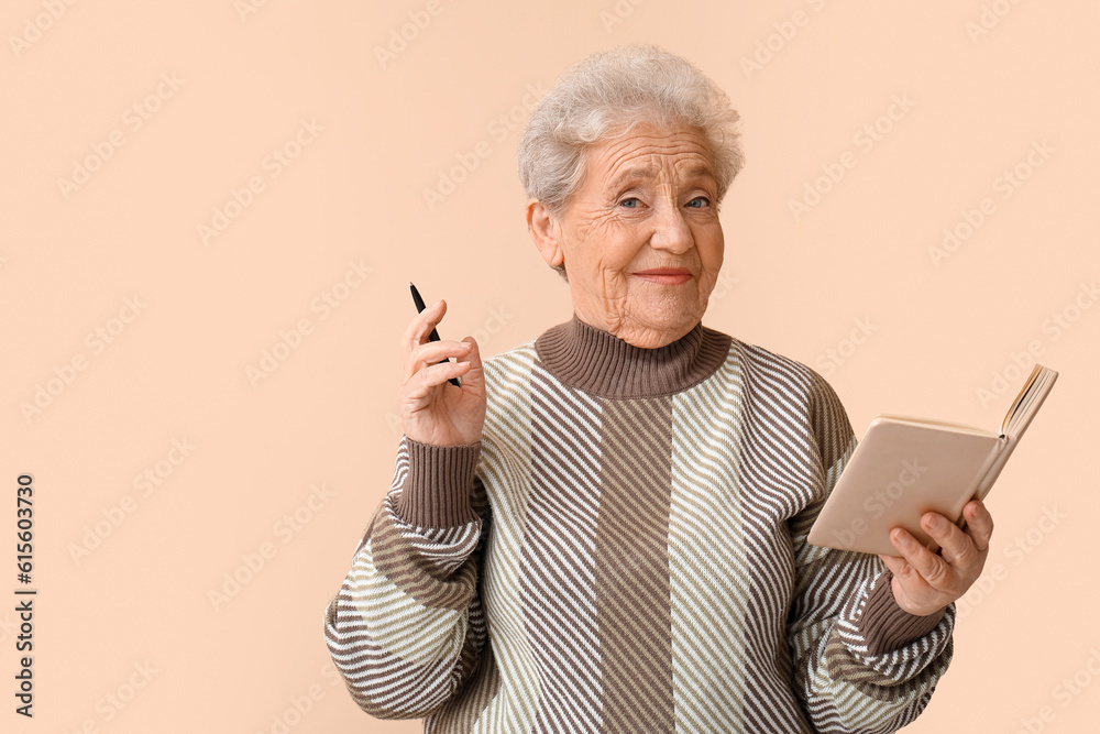 Senior woman with notebook on beige background