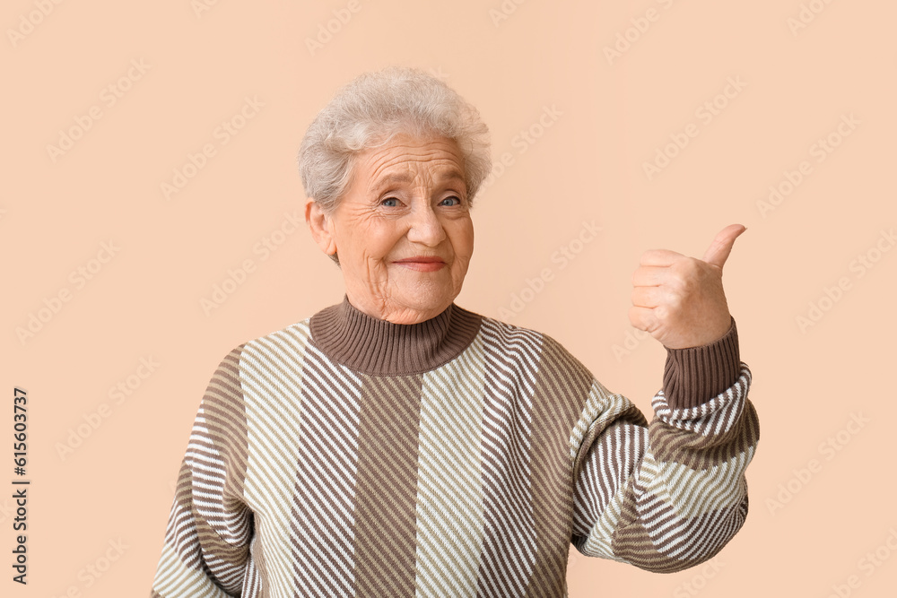 Senior woman showing thumb-up on beige background