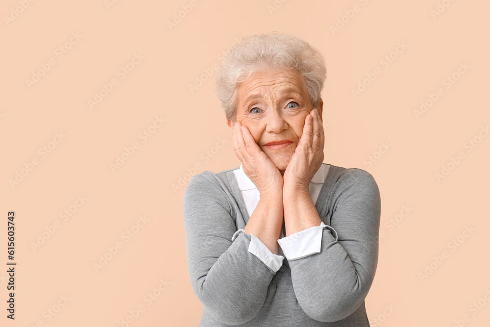 Surprised senior woman on beige background