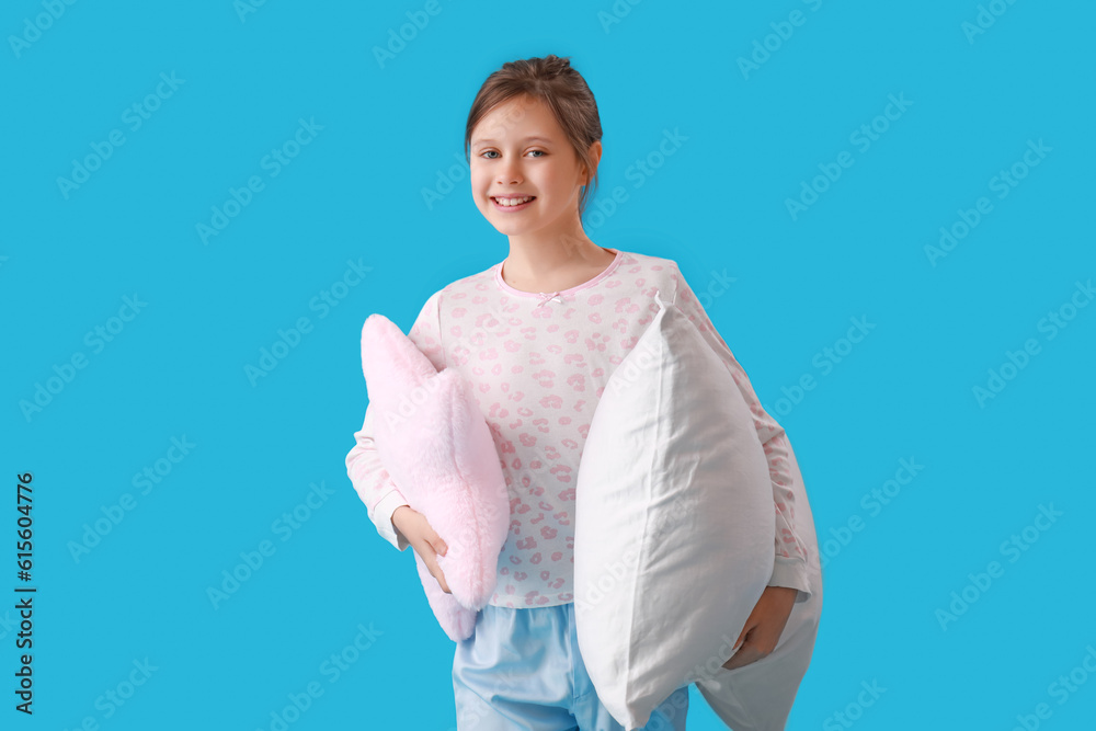 Little girl with pillows on blue background