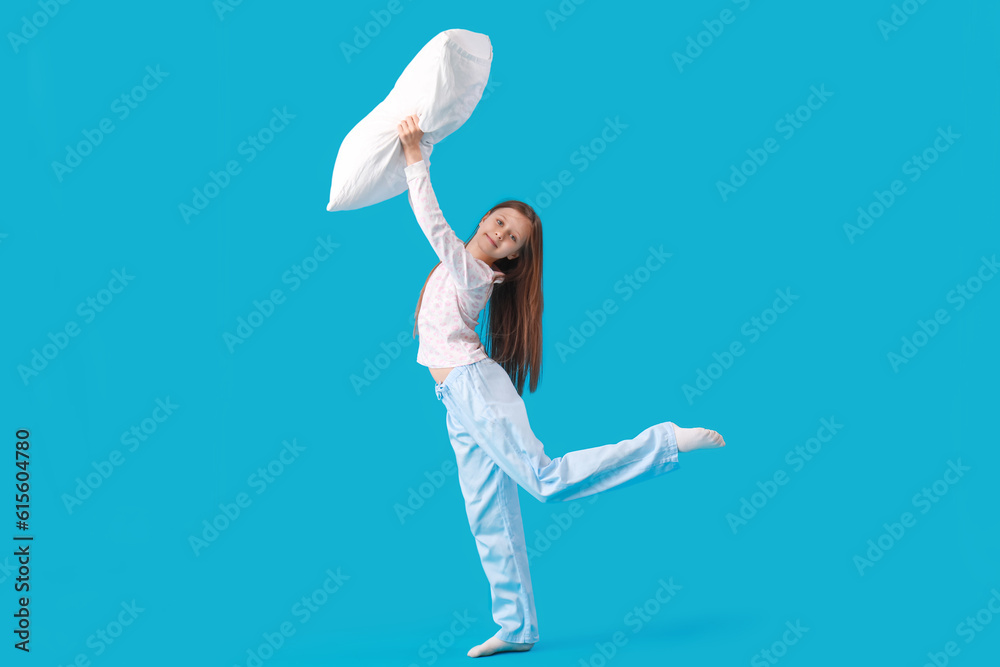 Little girl playing with pillow on blue background