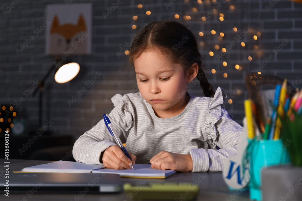 Little girl doing lessons at home late in evening