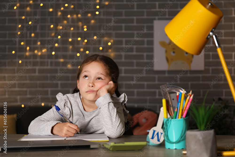 Tired little girl doing lessons at home late in evening