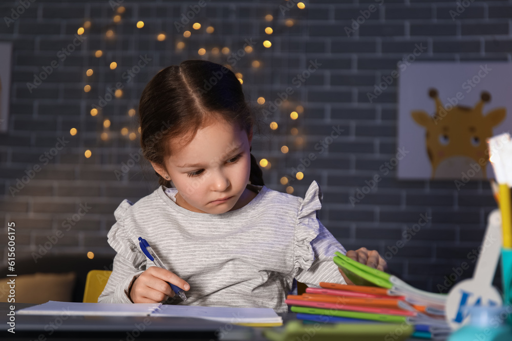 Little girl doing lessons at home late in evening