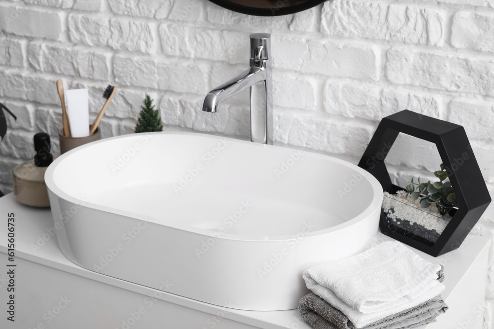 Sink bowl and bath accessories on table in bathroom, closeup