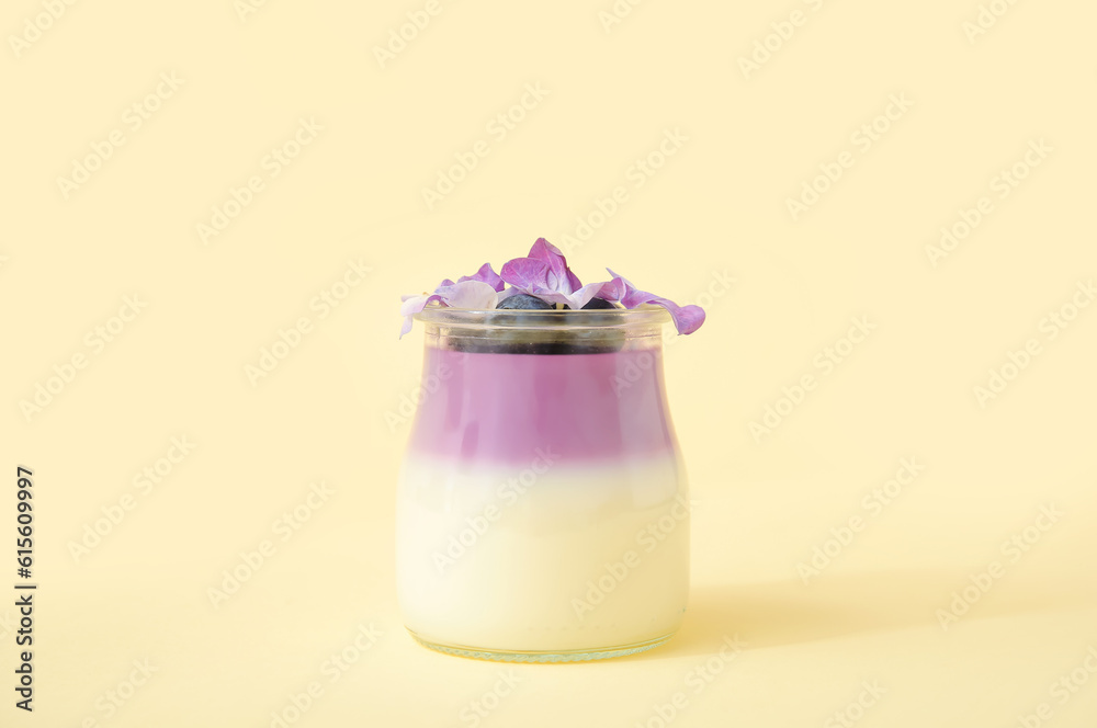 Glass of panna cotta with blueberry and beautiful hydrangea flowers on beige background