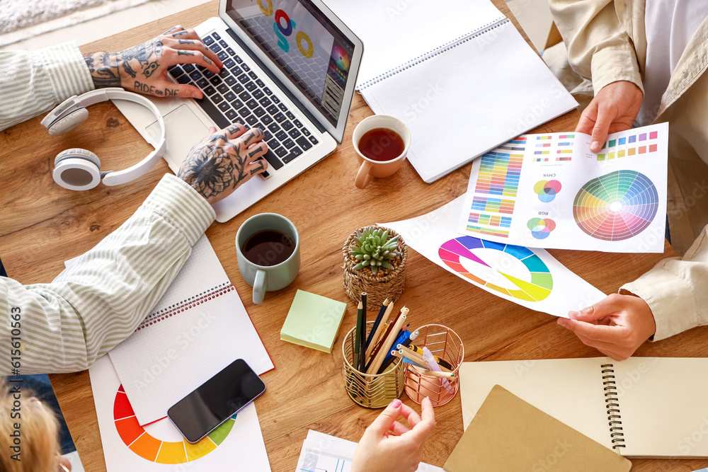 Team of graphic designers working with color palettes at table in office, closeup