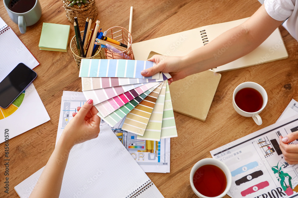 Female graphic designers working with color palettes at table in office, closeup