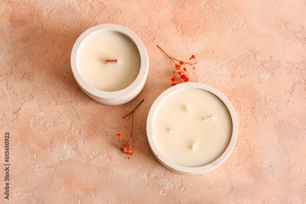 Holders with candles and flowers on pink background