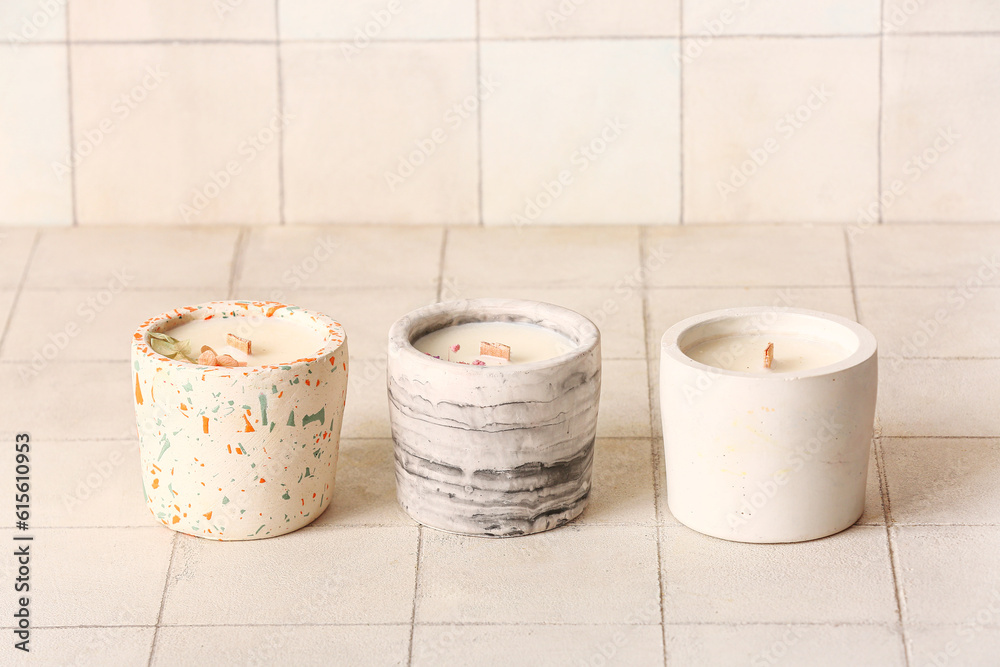 Holders with candles on white tile background