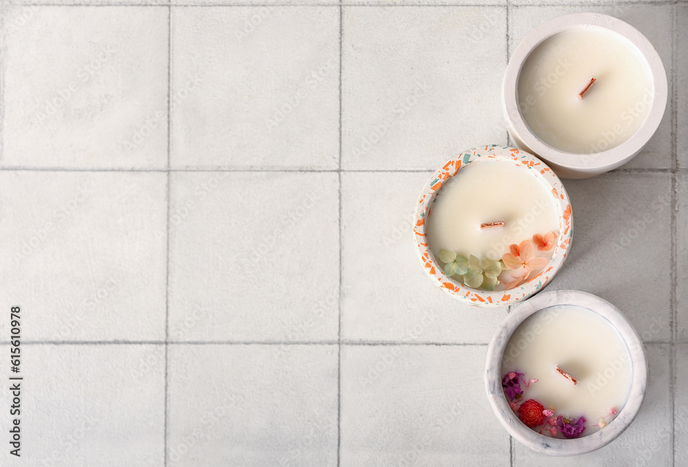 Holders with candles on white tile background