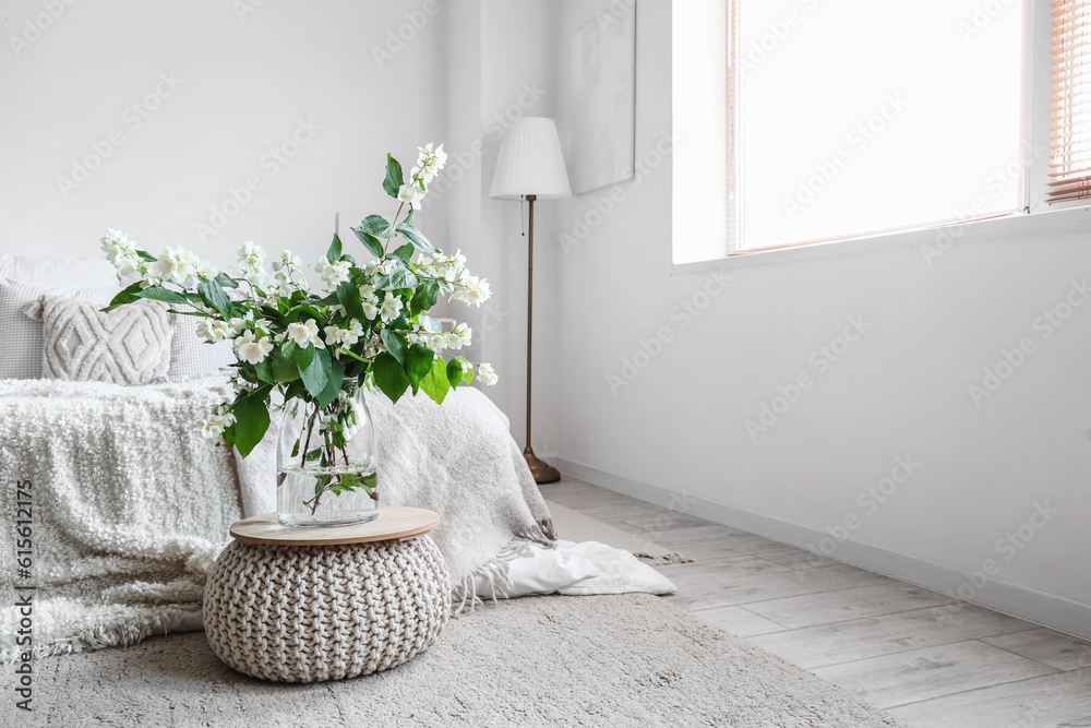 Interior of light bedroom decorated with blooming jasmine flowers in vase