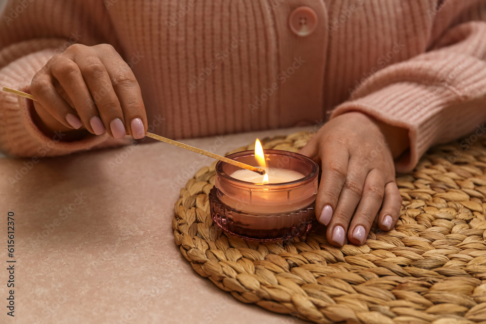 Woman lightning candle on table in evening, closeup