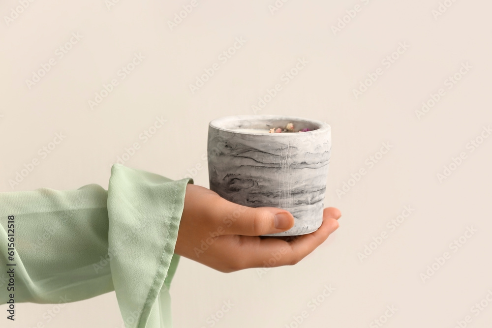 Woman holding candle on light background