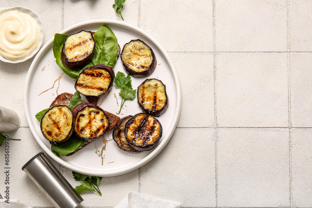 Toasts with delicious grilled eggplants and sauce on light background