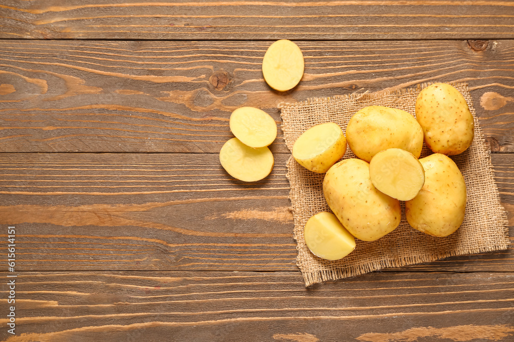 Raw baby potatoes and slices on wooden background