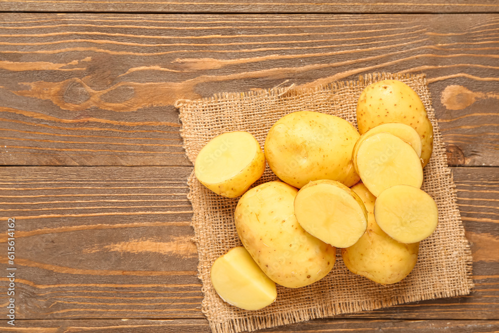 Raw baby potatoes and slices on wooden background