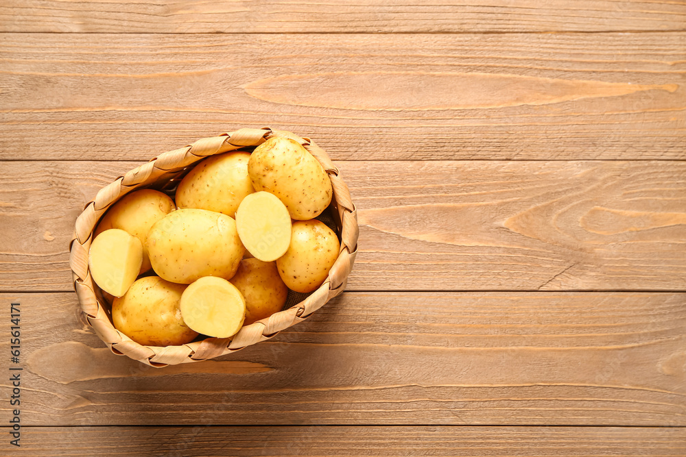 Wicker basket with raw baby potatoes on wooden background