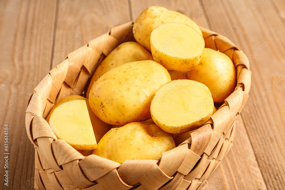 Wicker basket with raw baby potatoes on wooden background