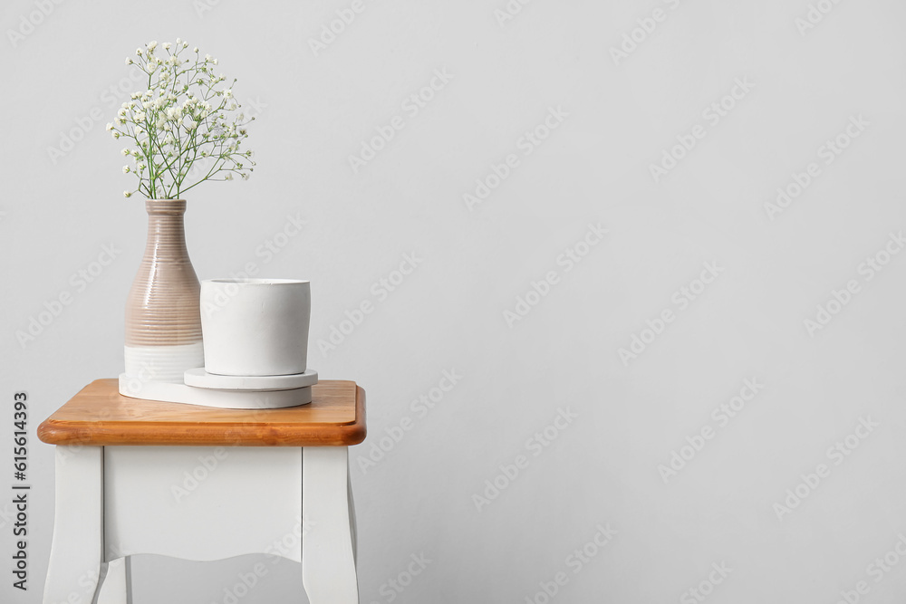 Gypsophila flowers and candle on chair near light wall in room