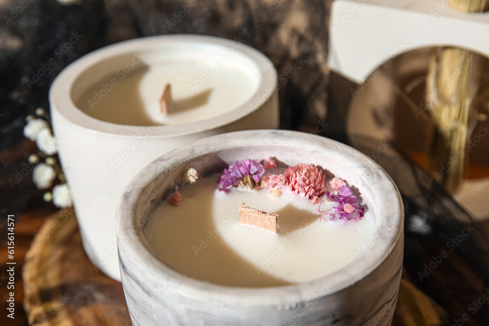 Holders with candles and flowers on table in room, closeup