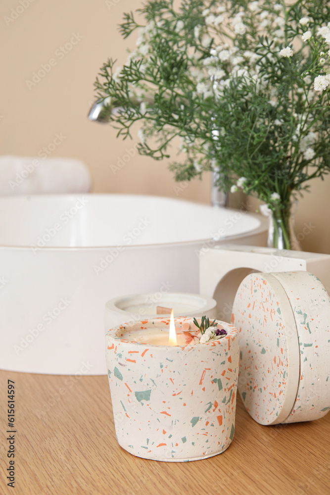 White sink, gypsophila flowers and candles on table in bathroom, closeup