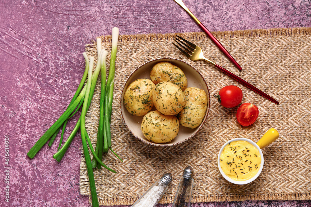 Plate of boiled baby potatoes with dill and sauce on purple background