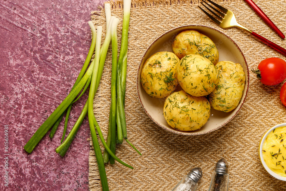 Plate of boiled baby potatoes with dill and sauce on purple background