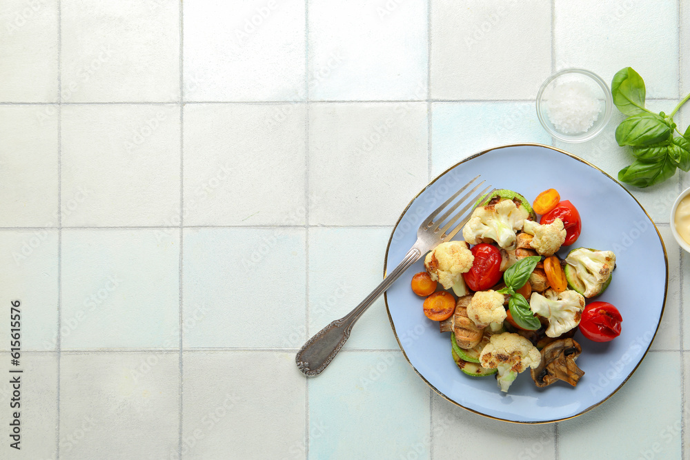 Plate with grilled vegetables and basil on white tile background