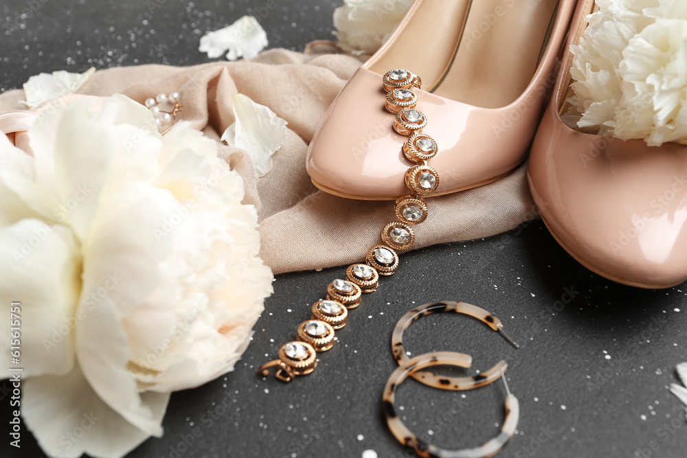 Stylish female accessories, high heels and beautiful peony flowers on dark background, closeup