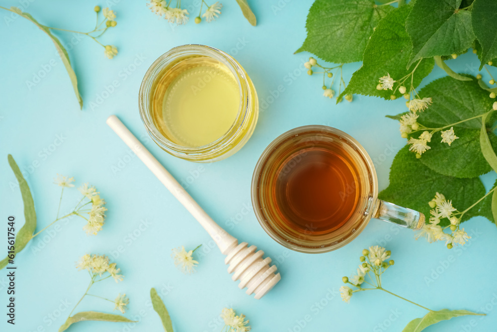 Glass cup of linden tea and jar with honey on blue background