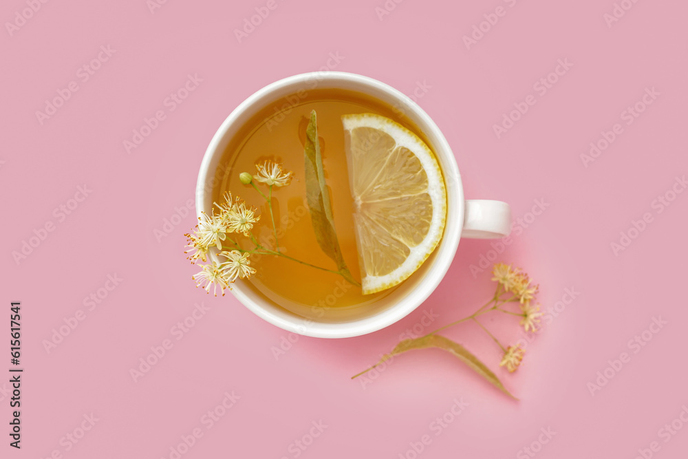 Cup of linden tea with lemon on pink background