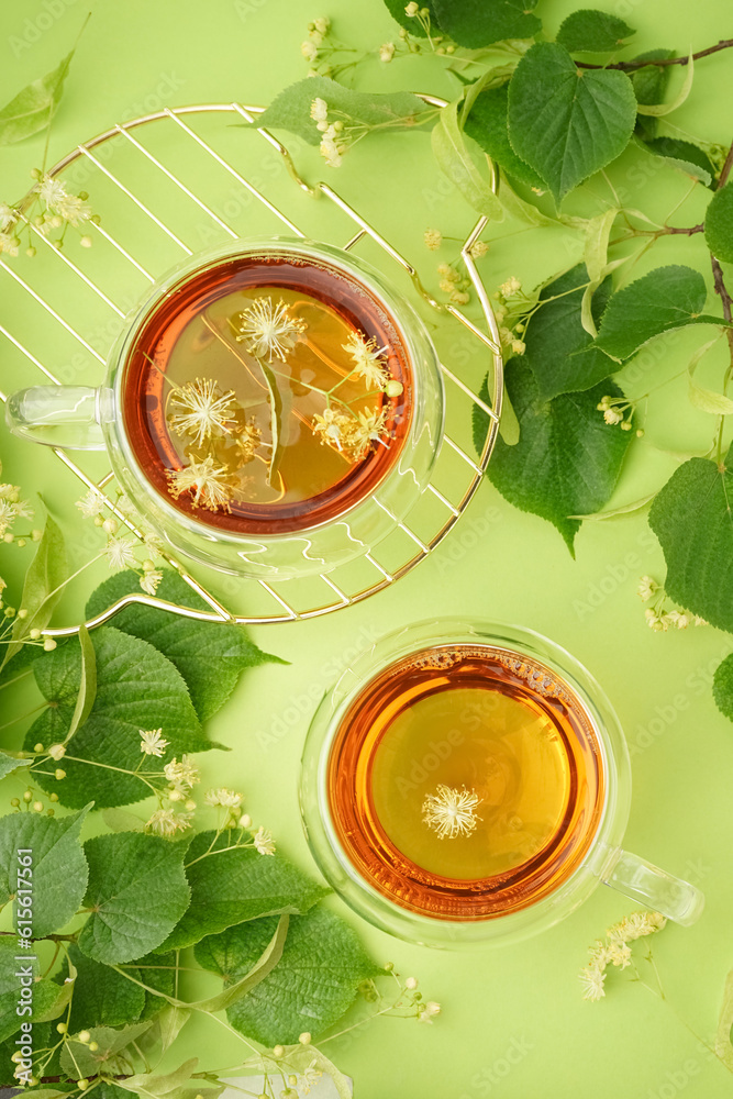 Stand with glass cups of linden tea on green background