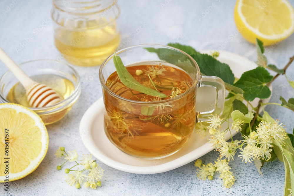 Glass cup of linden tea and bowl with honey on white background