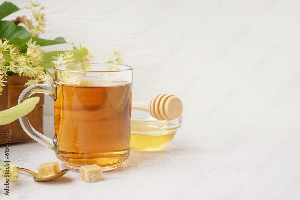 Glass cup of linden tea and bowl with honey on white background