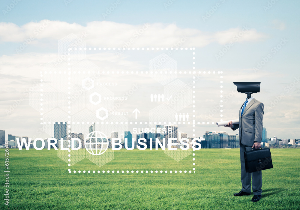 Camera headed man standing on green grass against modern cityscape