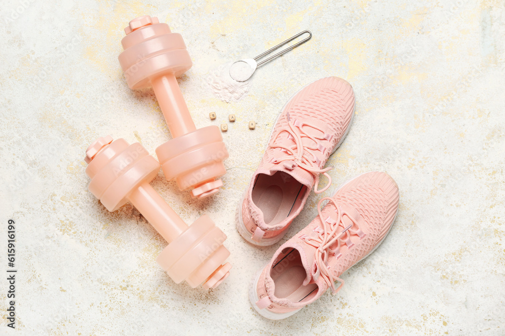 Dumbbells, shoes and scoop of amino acid supplement on light background