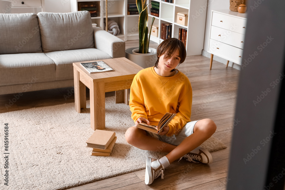 Teenage boy reading book on floor at home