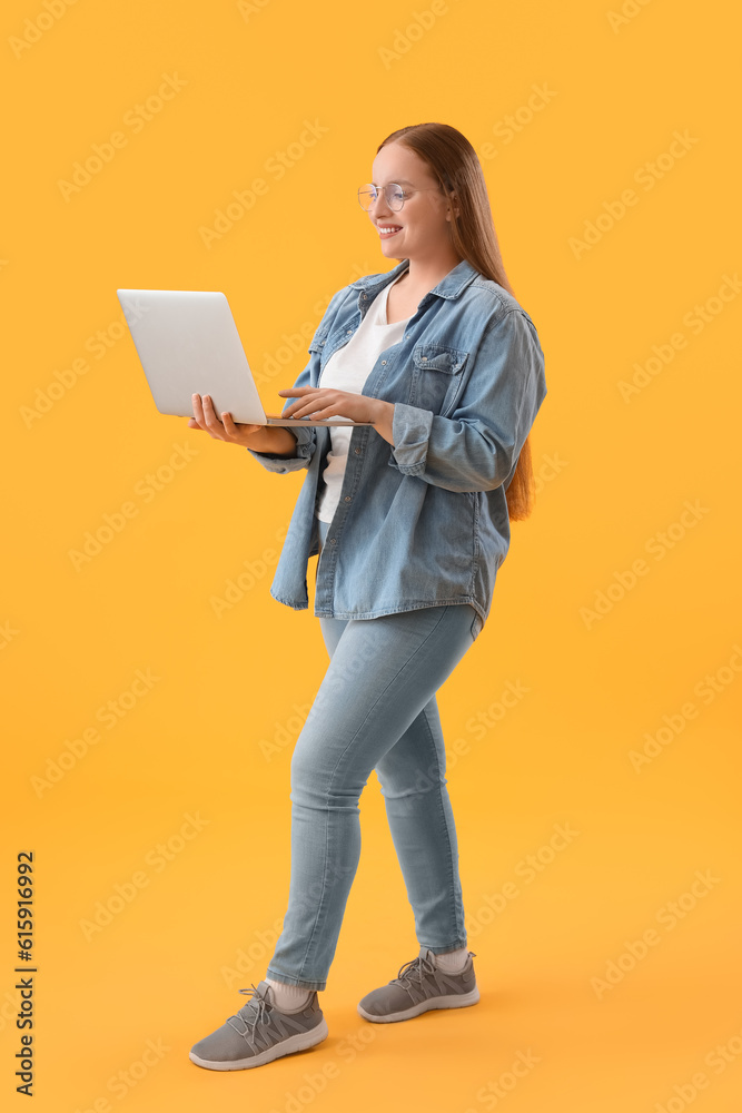 Female programmer working with laptop on yellow background